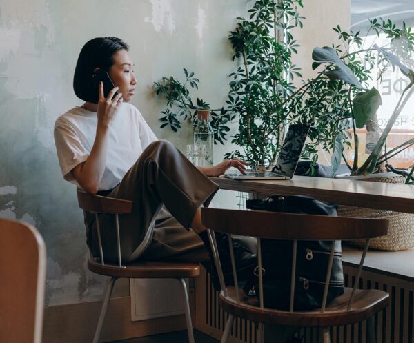 Person seated at desk with laptop computer in front of large window with plants.